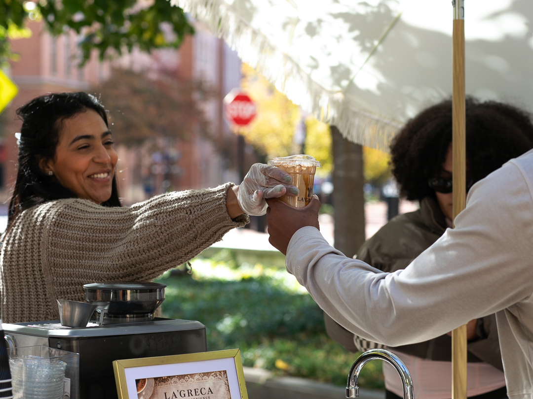 Yimelka handing a coffee to a guest